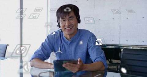Asian manager engaging in virtual meeting with tablet and smart icons