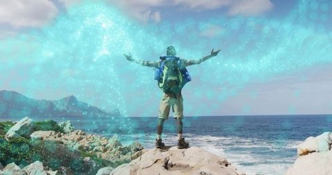 Backpacker standing on rocky coast embracing turquoise nebula over ocean horizon