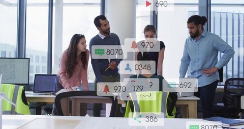 Team reviewing data with notification overlays in open-plan office wearing hi-vis vests