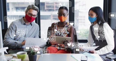 Diverse Team Discussing Social Media Statistics Wearing Masks