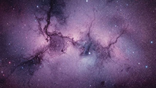 Vibrant pink emission nebula with stars and dust lanes in deep space