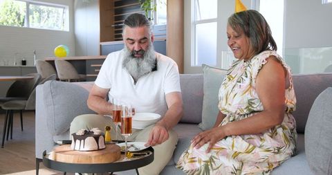 Senior Couple Celebrating with Cake and Champagne at Home