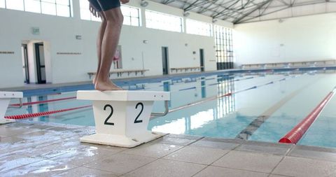 Swimmer ready on starting block in indoor pool