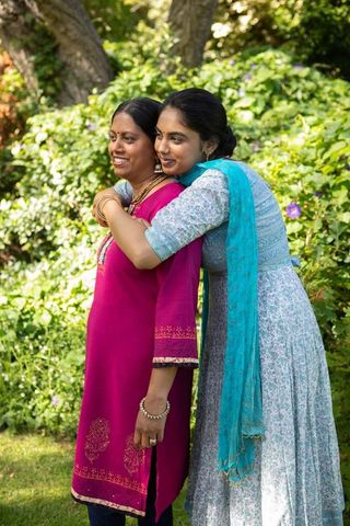 Indian mother and daughter hugging in lush backyard