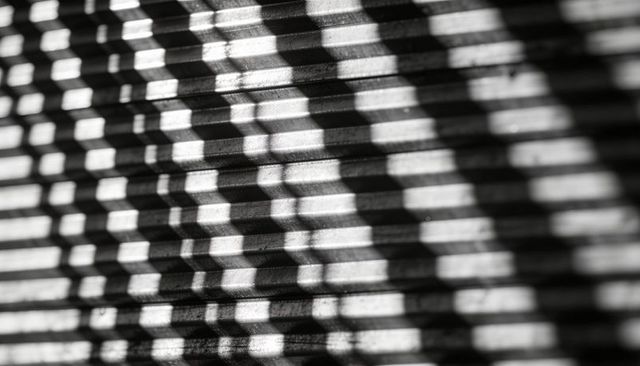 Venetian blind shadows creating geometric stripes and dusty texture in black and white