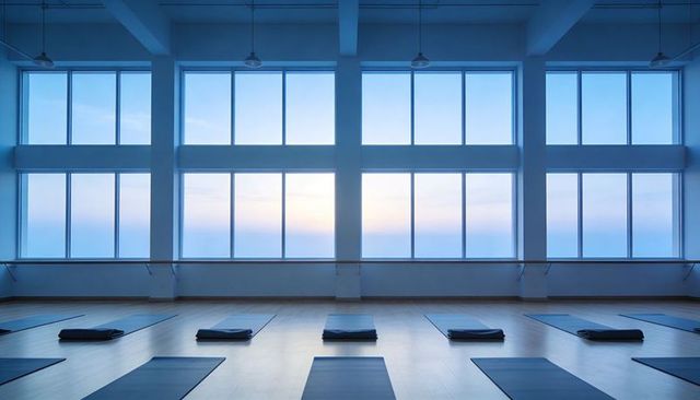 Tranquil sunrise minimalist yoga studio with neat mats and bolsters in blue-lit room