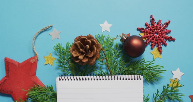 Image of christmas decorations with notebook and copy space on blue background. christmas, tradition and celebration concept.