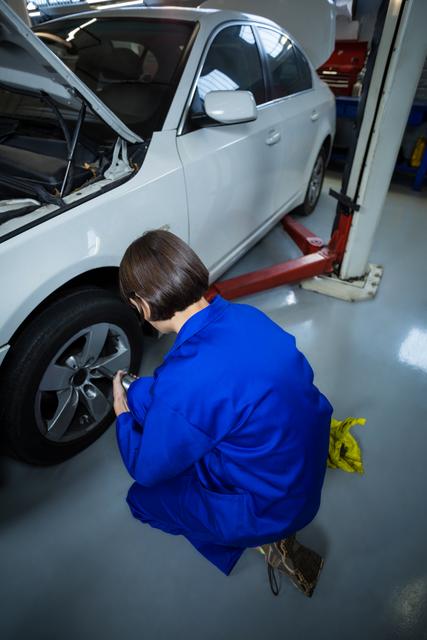 Female mechanic fixing a car wheel with pneumatic wrench - Download Free Stock Photos Pikwizard.com