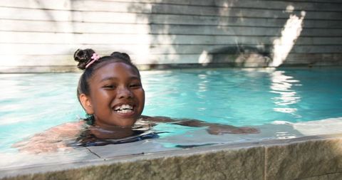 Joyful Girl Playing in Backyard Swimming Pool on Sunny Day