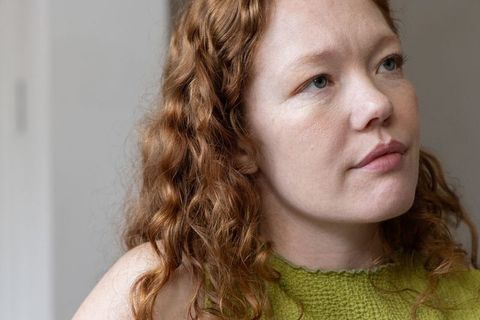 Contemplative redhead woman wearing green knit sleeveless top closeup portrait natural light