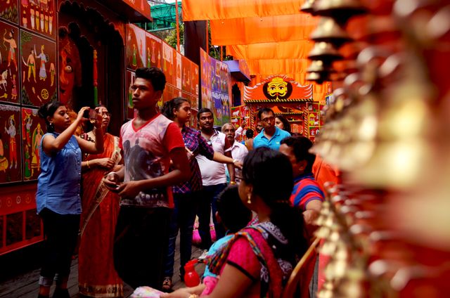 Crowded Indian market depicted during a festival with people moving through narrow streets adorned with colorful decorations and bells. Traditional attire is worn by many people, enhancing the cultural ambience. This stock photo is ideal for use in travel blogs, articles about Indian culture and festivals, promotional materials for tourism, and any content celebrating multicultural events.