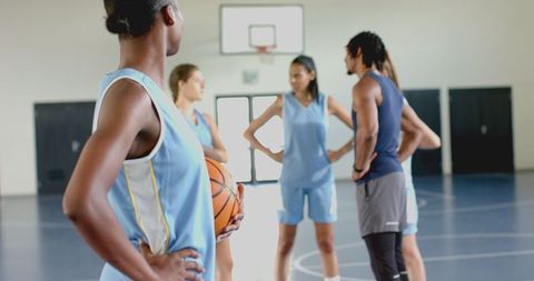 Diverse Basketball Team Strategizing on Indoor Court
