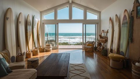Beachfront longboard lounge opening onto ocean view through sliding glass doors, coastal interior