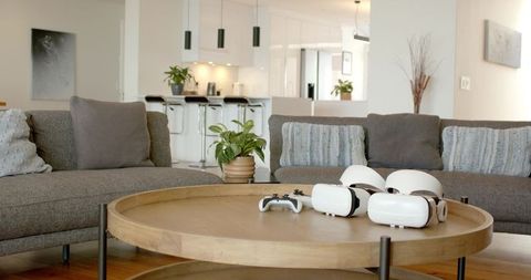 Minimalist living room with white vr headsets and controller on round wooden coffee table