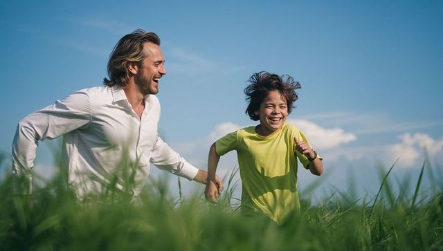 Father and son running through tall green grass holding hands under clear blue sky
