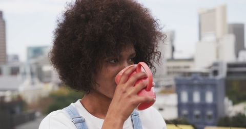 Young Woman Enjoying Coffee on Rooftop with Urban Skyline