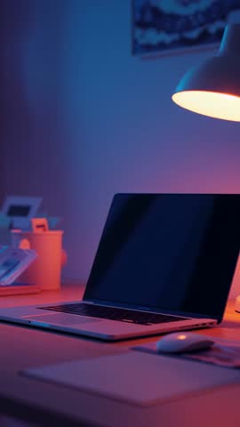 Vertical video showing cozy modern home workspace with laptop under warm lamp glow