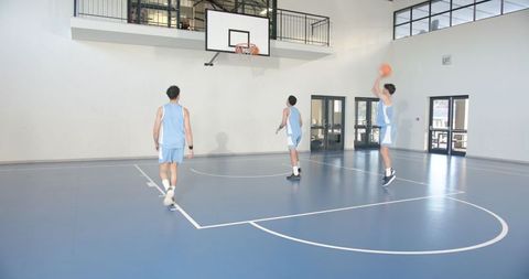 Teammates on Indoor Basketball Court Shooting in Unison