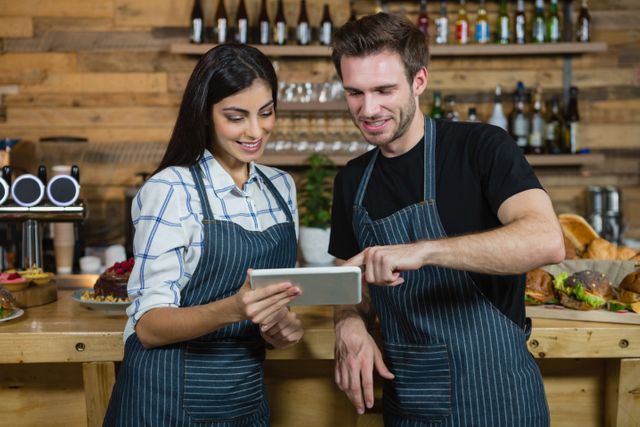Waiter and waitresses using digital tablet at counter in cafÃ©