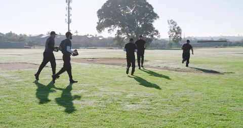 Umpires walking across sunlit baseball diamond holding protective masks