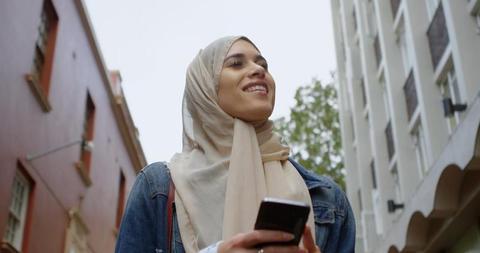 Muslim Woman Walking In Urban Environment While Using Smartphone - Download Free Stock Images Pikwizard.com