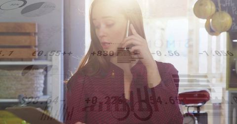 Backlit entrepreneur holding smartphone checking tablet with analytics overlay at cafe