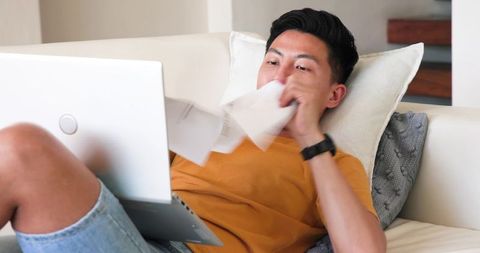 Young Man Relaxing with Laptop on Sofa at Home