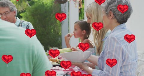 Happy Family Dining Outdoors Surrounded by Heart Balloons