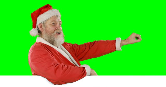 Santa Claus in traditional red costume smiling and pointing against green screen background, useful for holiday advertising, festive promotions, or Christmas-themed projects.