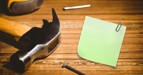 Memo note with hammer and nails on wooden desk
