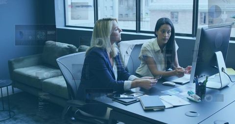 Female Professionals Collaborating and Reviewing Analytics on Monitor in Modern Office