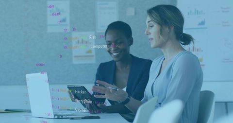 Female professionals collaborating on digital analytics with laptop and tablet in office