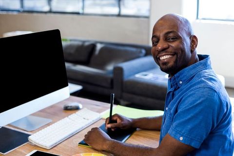 Creative Designer Smiling at Workdesk with Digital Tools - Download Free Stock Images Pikwizard.com