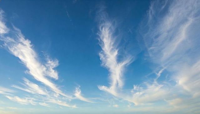 Stretching cirrus clouds filling blue sky with wispy feathered trails
