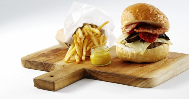 A classic American cheeseburger meal with fries and mustard is displayed on a wooden board. - Download Free Stock Photos Pikwizard.com