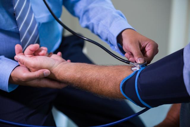Male doctor checking blood pressure of patient at the hospital