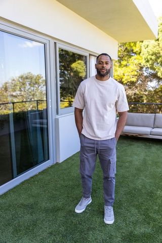 Mature african american man standing on modern balcony wearing casual tee and cargo pants
