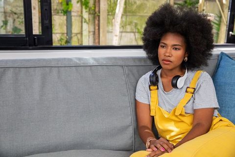 Thoughtful woman relaxing on sofa with headphones