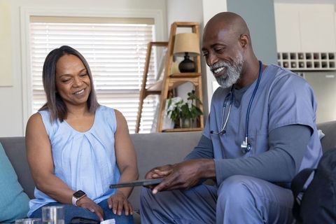 African american doctor consulting middle-aged woman at home using tablet for telehealth