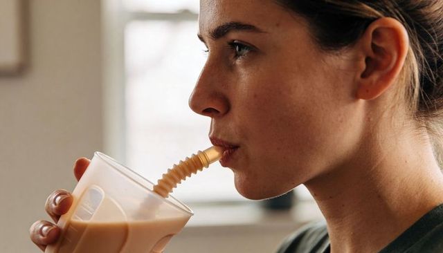 Young woman sipping iced coffee through corrugated straw - closeup profile, natural light