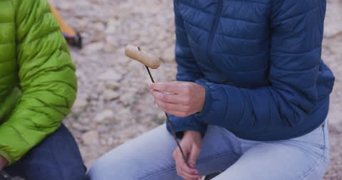 Couple Roasting Sausages by Campfire
