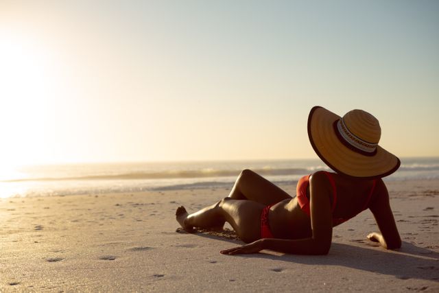 Rear view of woman in hat relaxing on the beach