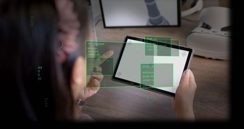 Mid-adult woman holding tablet with holographic ar interface at modern wooden desk