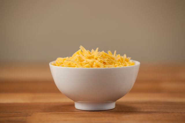 Grated cheese in a bowl on wooden table