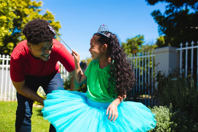 Father and daughter enjoying a sunny day in the backyard, with the daughter dressed in a fairy costume. Perfect for use in family-oriented advertisements, parenting blogs, lifestyle magazines, and promotional materials highlighting family bonding and outdoor activities.