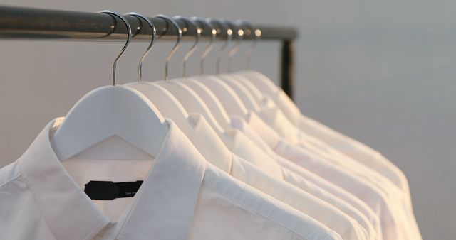 Row of white shirts hanging on black hanger rack, copy space. Clothes, hanging and hanger rack concept, unaltered.