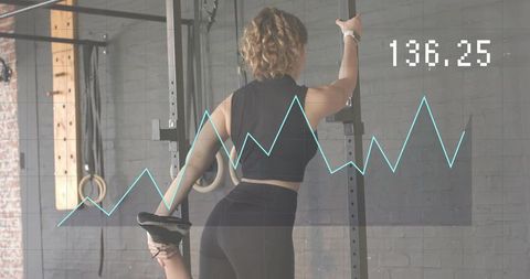 Woman stretching leg at gym rack with fitness data overlay 136.25, athletic training