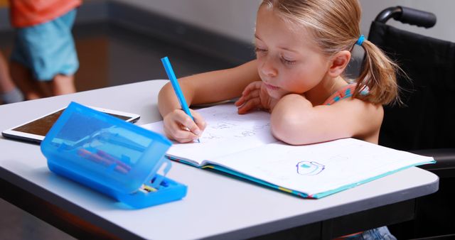 Young Girl in Wheelchair Enjoying Schoolwork at Desk - Download Free Stock Images Pikwizard.com