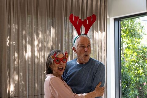Elderly couple celebrating with festive antlers at home