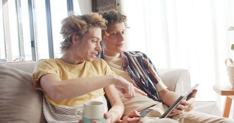 Happy Diverse Gay Couple Enjoying Time with Tablet at Home